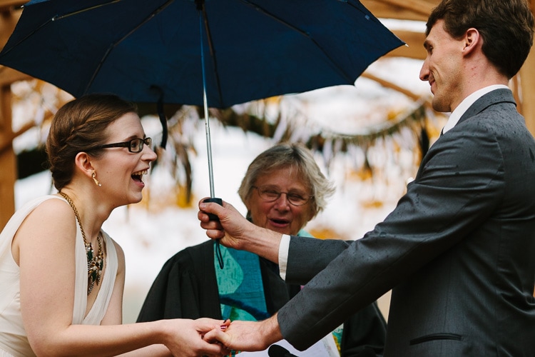 exchange of wedding rings under rain umbrella during a backyard Berkshires wedding ceremony