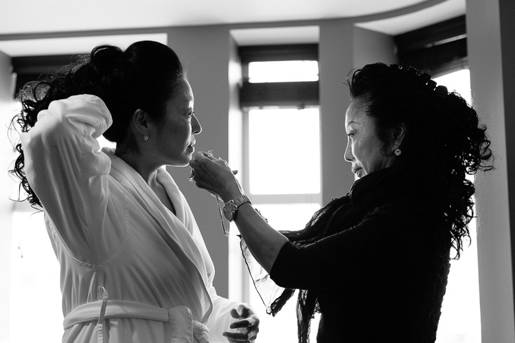 Bride's mom helps with necklace while getting ready for the wedding at Hotel Commonwealth