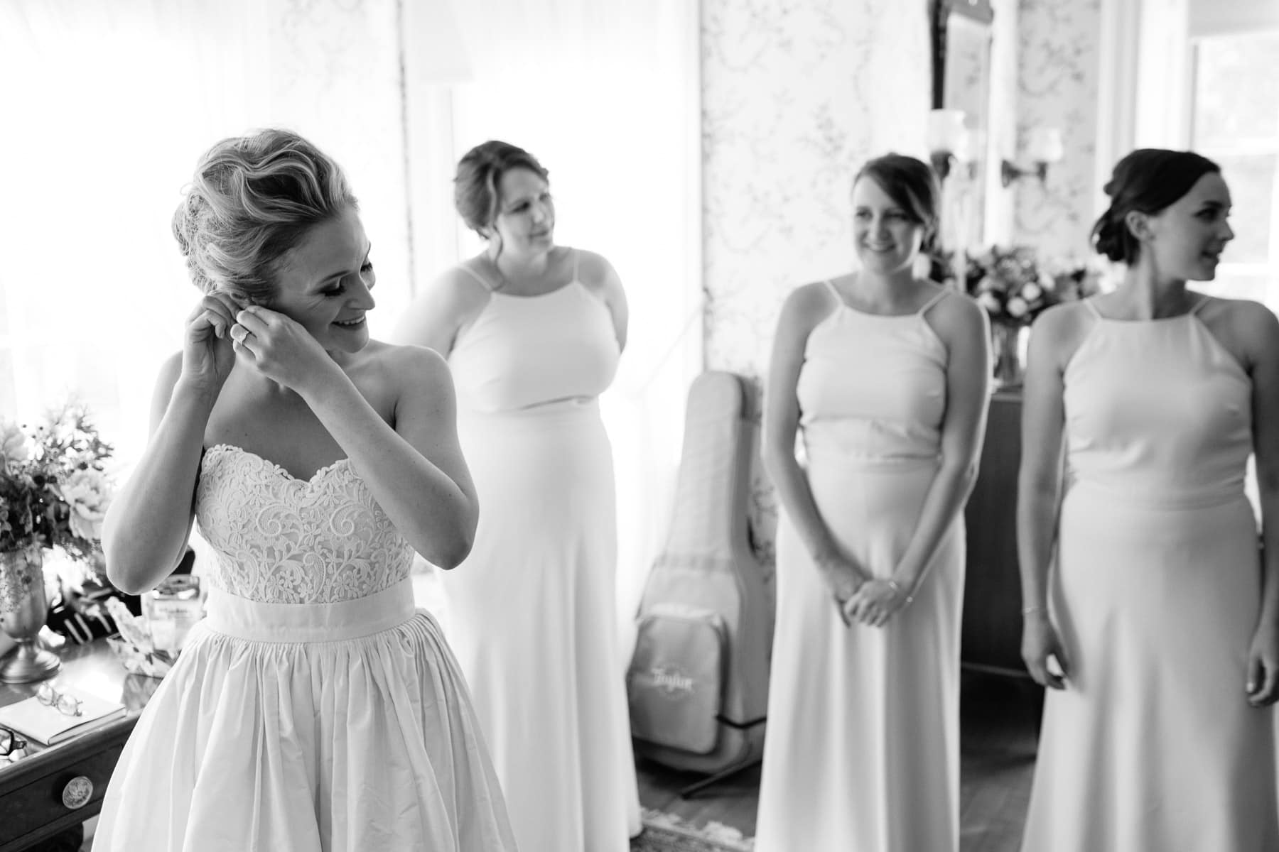 black and white photo of bridesmaids watching bride put on earrings in Lyman Estate bridal suite