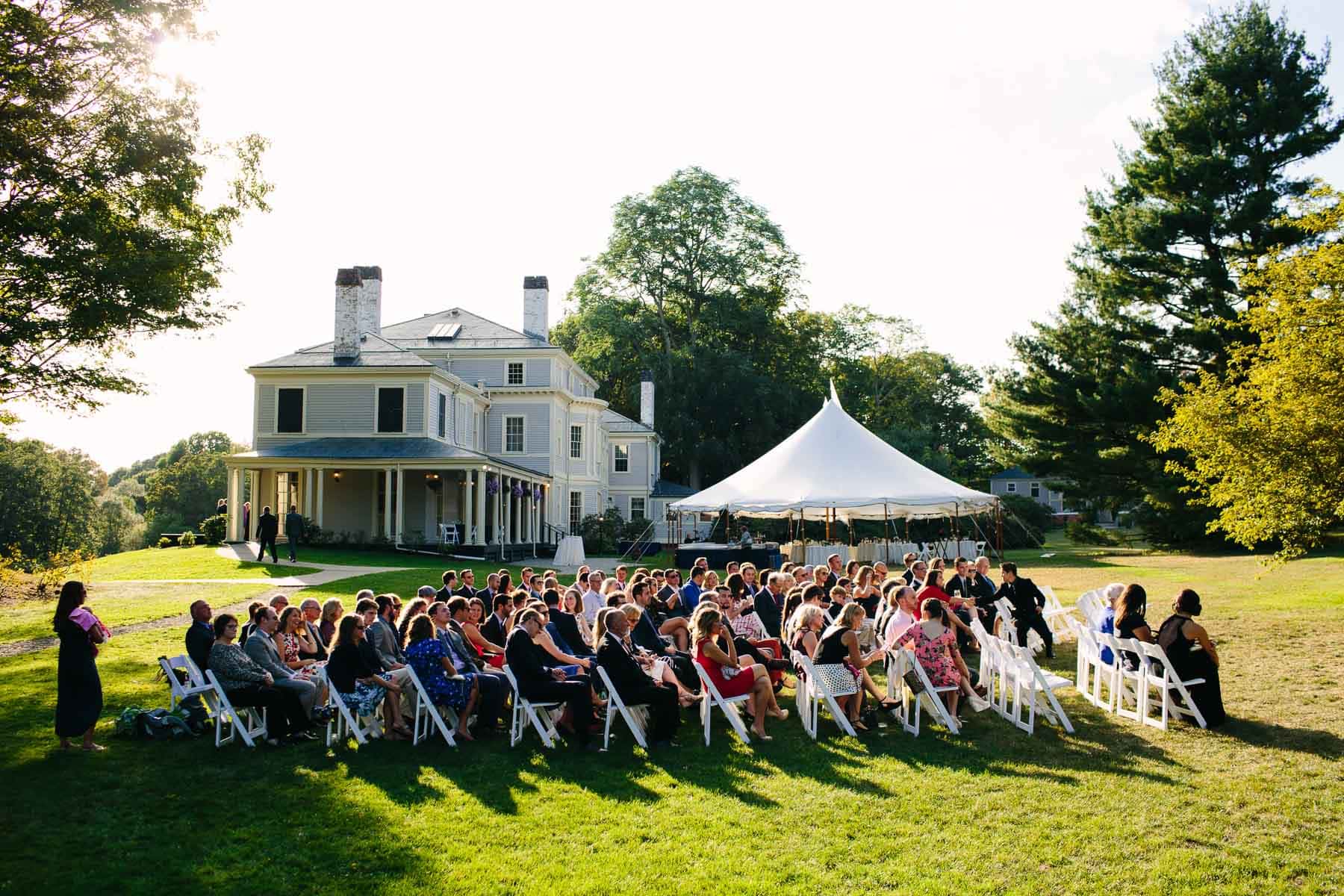 wedding ceremony on Lyman Estate lawn with house and sailcloth tent in background