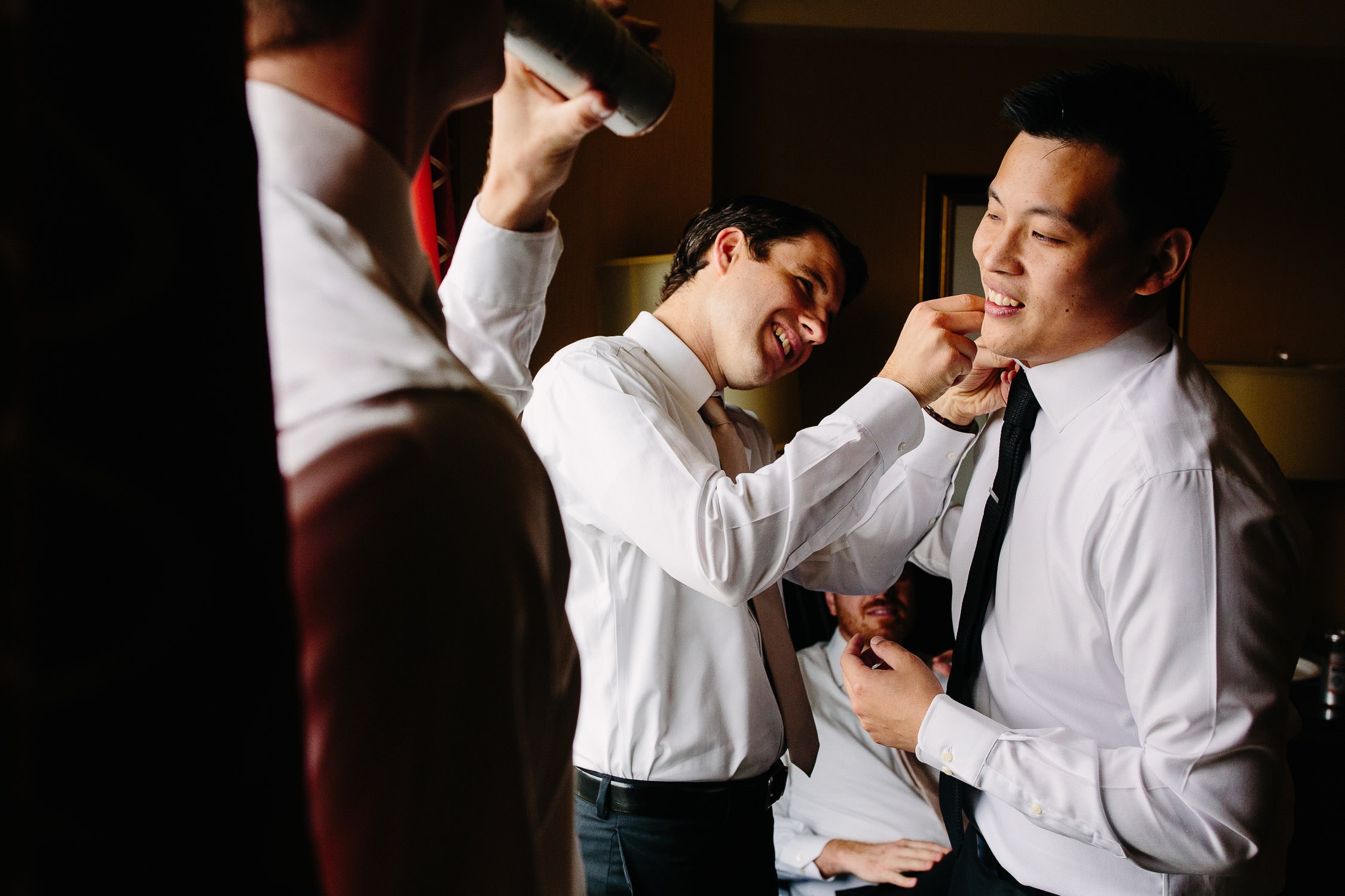 groomsmen helping groom fix his shirt collar before wedding