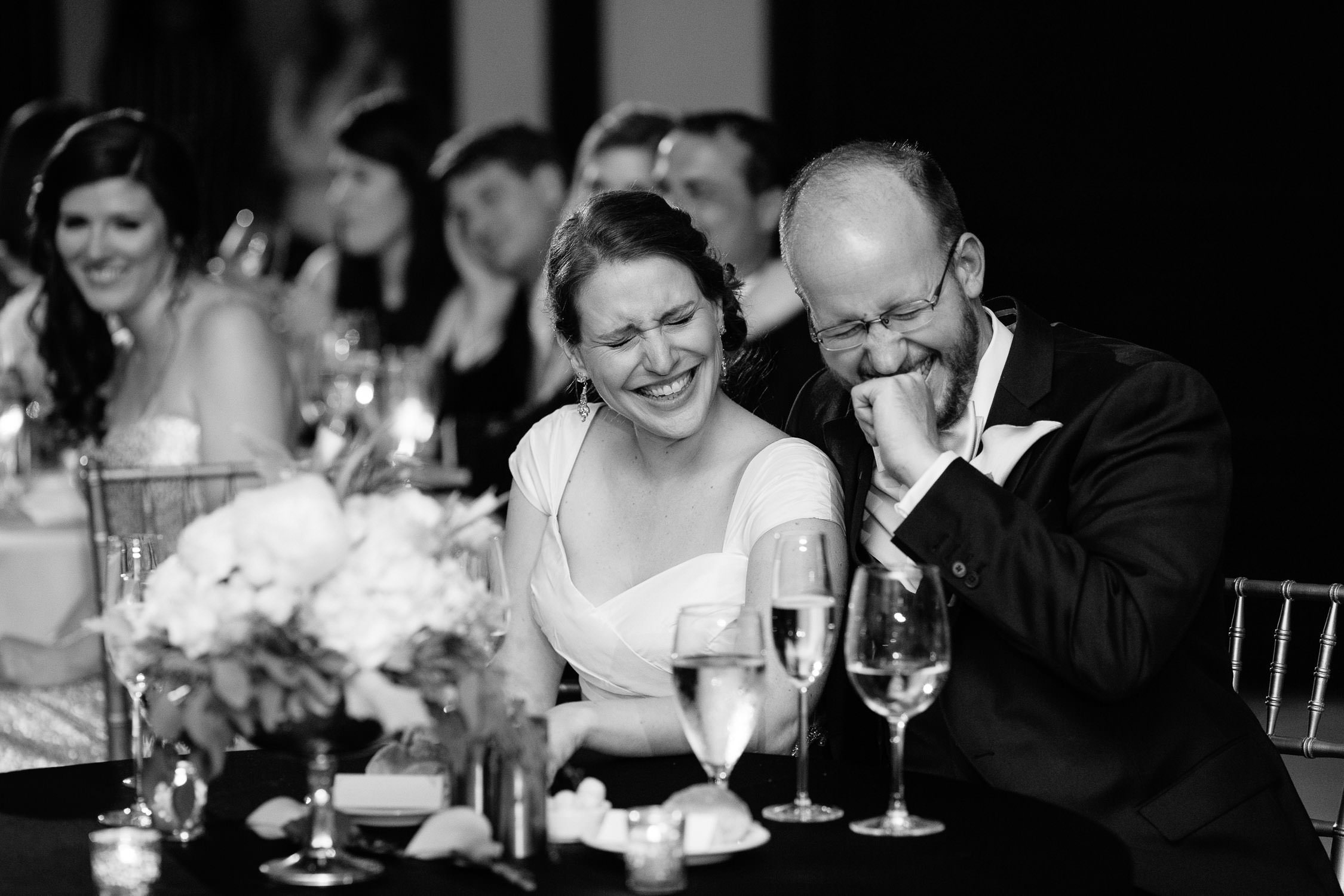 bride and groom stifle laugher during wedding reception