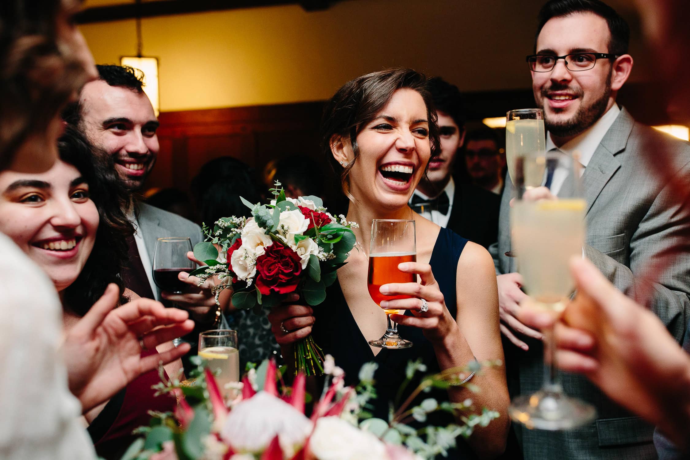 wedding party laughing with drinks in hand during toast