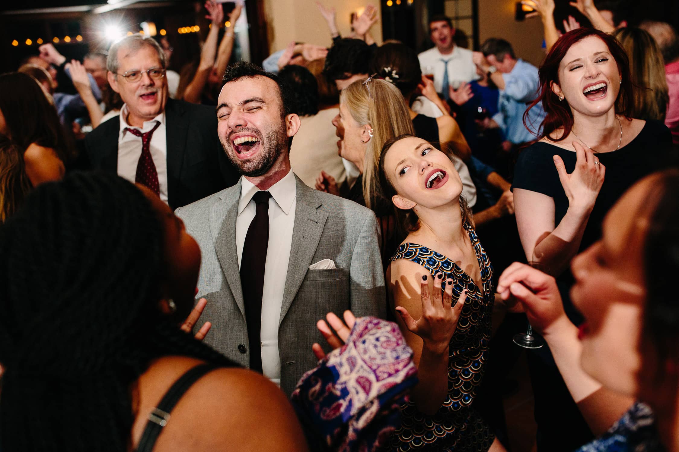 guests enthusiastically singing along on dance floor at wedding reception