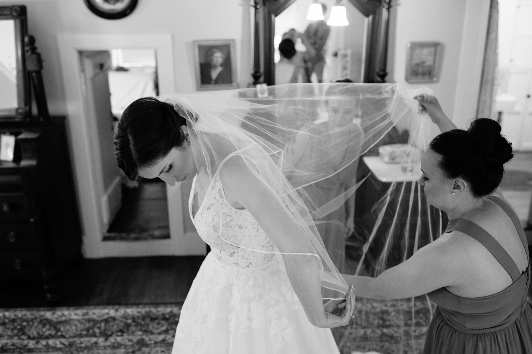 bride puts on veil with help from her sisters