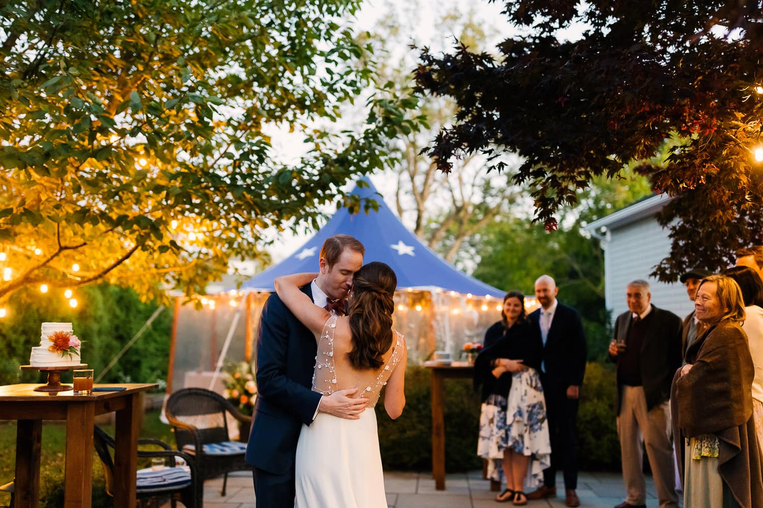 bride and groom share first dance at dusk in their backyard